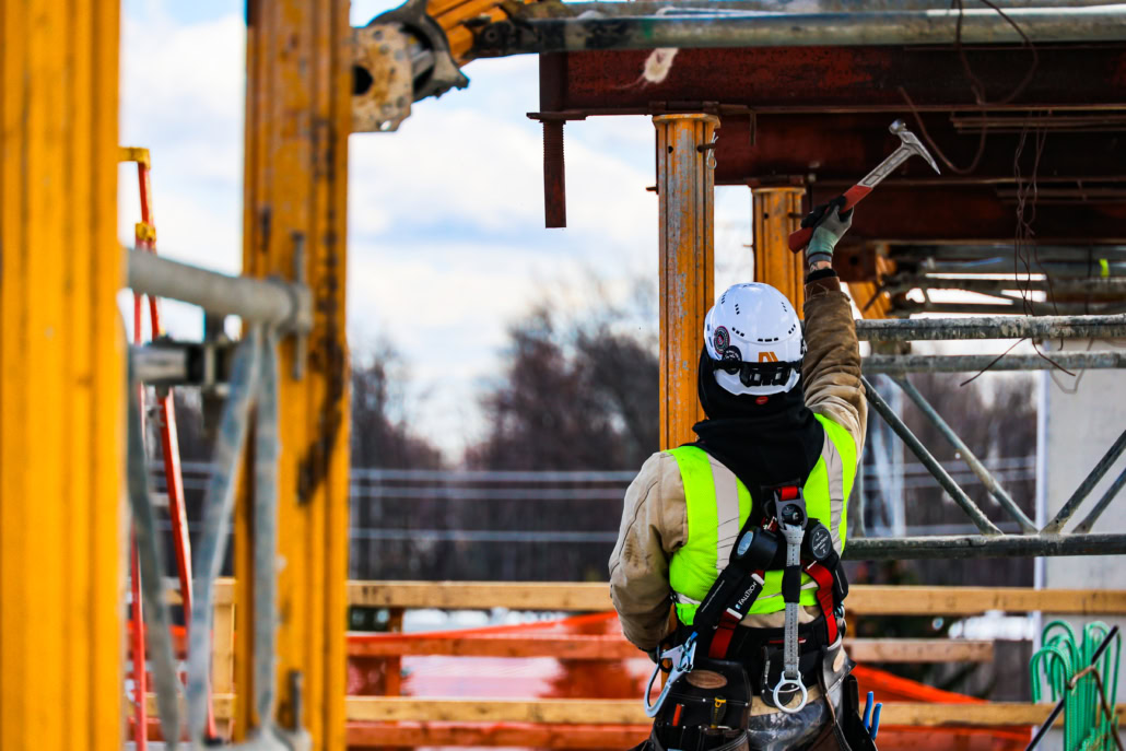 Union Carpenter swinging hammer outside on a job site in PPE safety equipment.